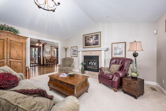 living room featuring carpet, baseboards, visible vents, a fireplace, and vaulted ceiling