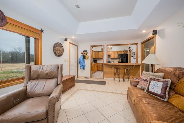 living area featuring light tile patterned floors, visible vents, recessed lighting, and a raised ceiling