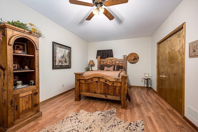 bedroom with baseboards, wood finished floors, visible vents, and ceiling fan