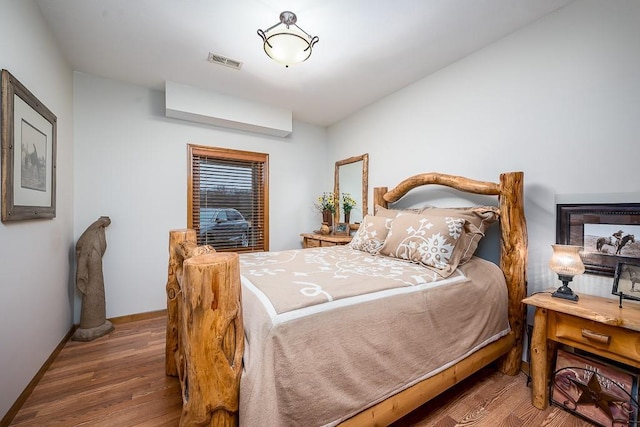 bedroom featuring visible vents, baseboards, and wood finished floors