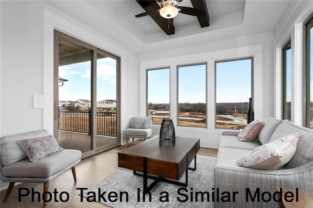 sunroom featuring a tray ceiling and a ceiling fan