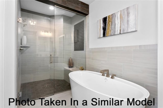 bathroom featuring a freestanding tub, a shower stall, and tile walls