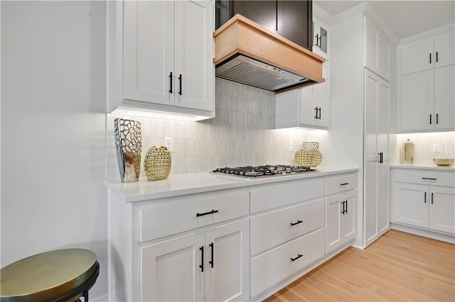 22109 W 93rd Ter, Lenexa, KS 66220 - kitchen with custom exhaust hood, stainless steel gas stovetop, backsplash, light countertops, and light wood finished floors