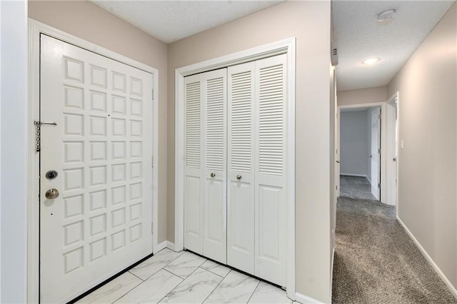 entryway featuring baseboards, marble finish floor, and a textured ceiling