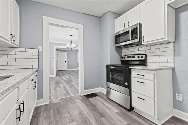 kitchen with backsplash, stainless steel appliances, light stone counters, light hardwood / wood-style floors, and white cabinets