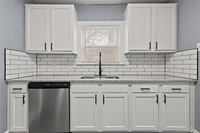 kitchen featuring sink, stainless steel dishwasher, white cabinets, and light stone counters