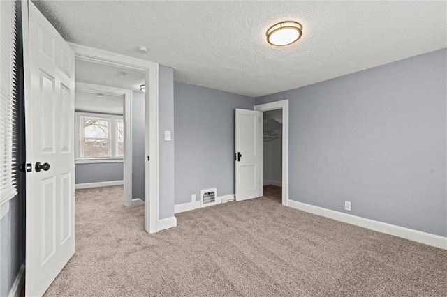 unfurnished bedroom featuring light colored carpet, a textured ceiling, and a closet