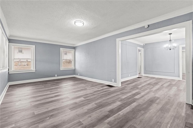 unfurnished room with hardwood / wood-style flooring, ornamental molding, a chandelier, and a textured ceiling