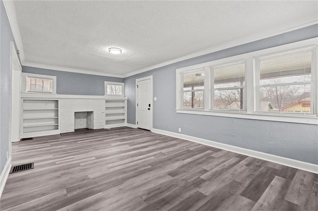 unfurnished living room with a fireplace, wood-type flooring, ornamental molding, a healthy amount of sunlight, and a textured ceiling