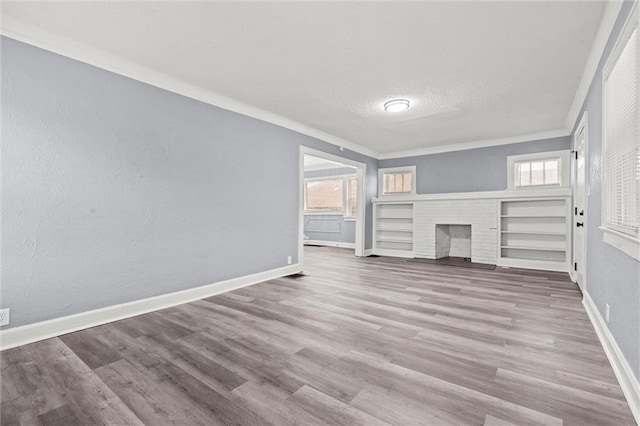 unfurnished living room with ornamental molding, wood-type flooring, a textured ceiling, and a fireplace