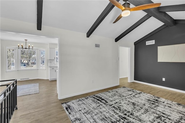 empty room with lofted ceiling with beams, ceiling fan with notable chandelier, and light wood-type flooring