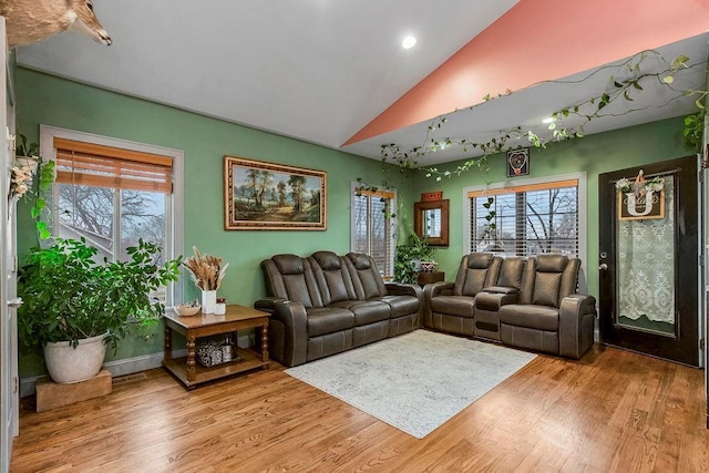 living room featuring lofted ceiling and light hardwood / wood-style flooring