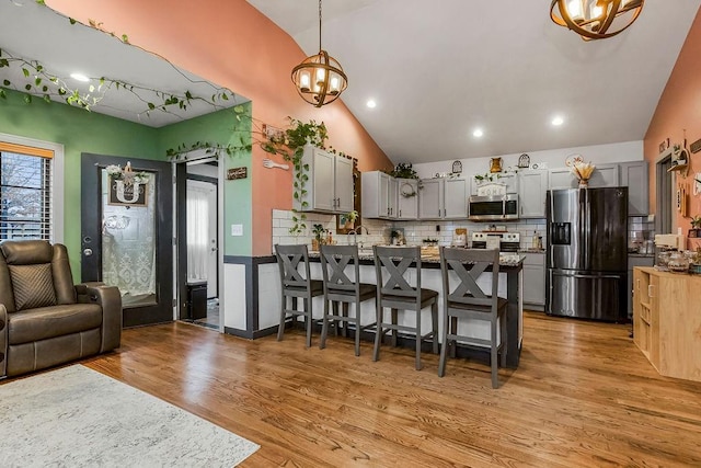 kitchen featuring gray cabinets, a breakfast bar, hanging light fixtures, stainless steel appliances, and kitchen peninsula