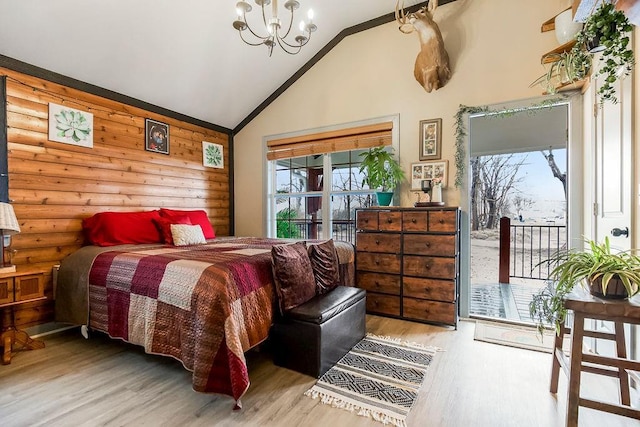 bedroom with hardwood / wood-style flooring, an inviting chandelier, access to outside, and multiple windows