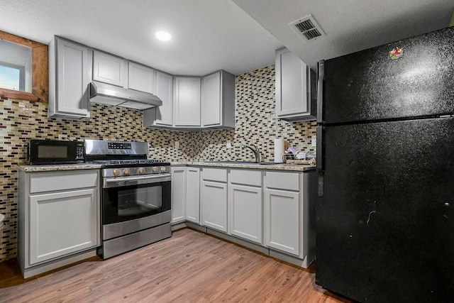 kitchen featuring sink, white cabinets, backsplash, black appliances, and light wood-type flooring