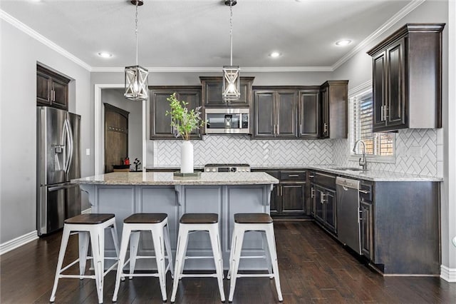 kitchen featuring decorative light fixtures, a center island, light stone countertops, stainless steel appliances, and a sink