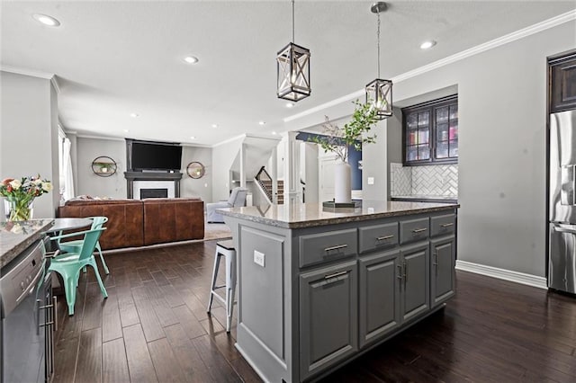 kitchen with pendant lighting, a breakfast bar area, gray cabinets, appliances with stainless steel finishes, and a kitchen island