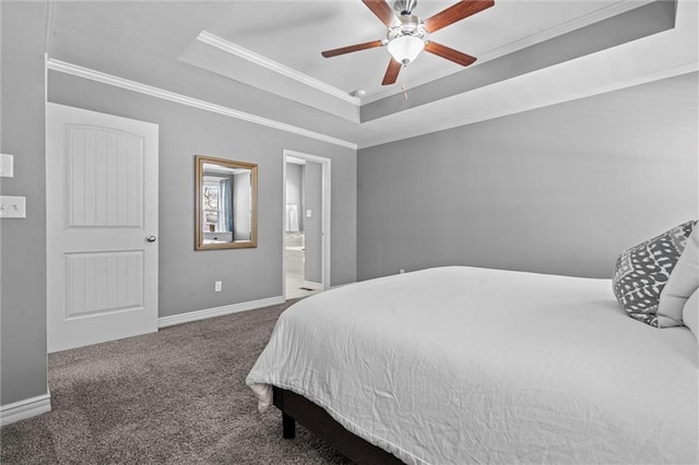 carpeted bedroom with a tray ceiling, crown molding, connected bathroom, ceiling fan, and baseboards