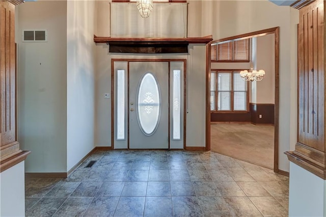 entrance foyer with carpet floors, a chandelier, and a high ceiling