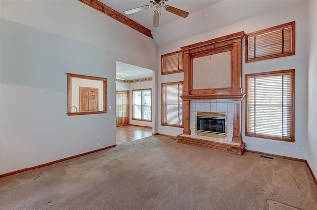 unfurnished living room featuring light carpet, high vaulted ceiling, a tile fireplace, and ceiling fan