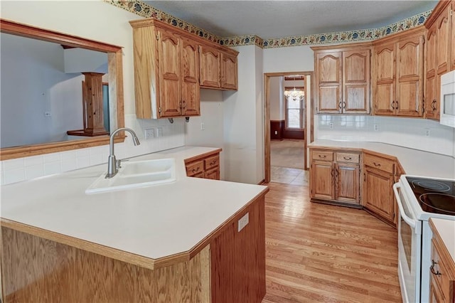 kitchen featuring tasteful backsplash, sink, white appliances, kitchen peninsula, and light wood-type flooring