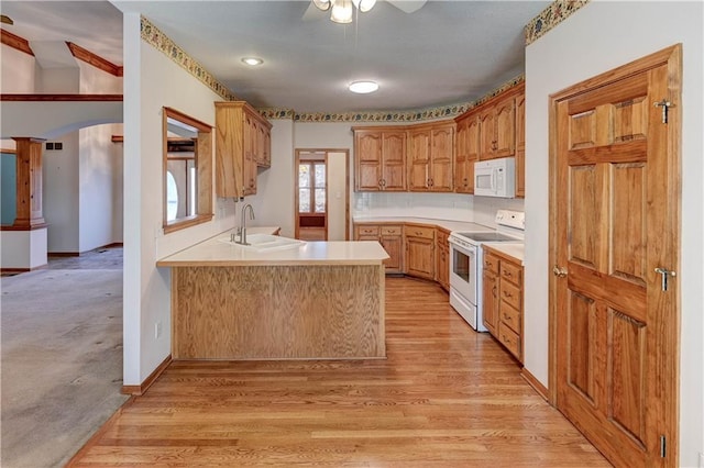 kitchen featuring light wood-type flooring, sink, white appliances, and kitchen peninsula