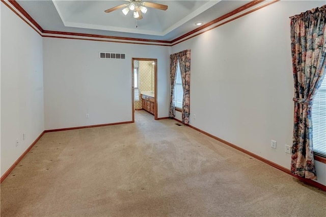 carpeted empty room featuring a raised ceiling, crown molding, and ceiling fan