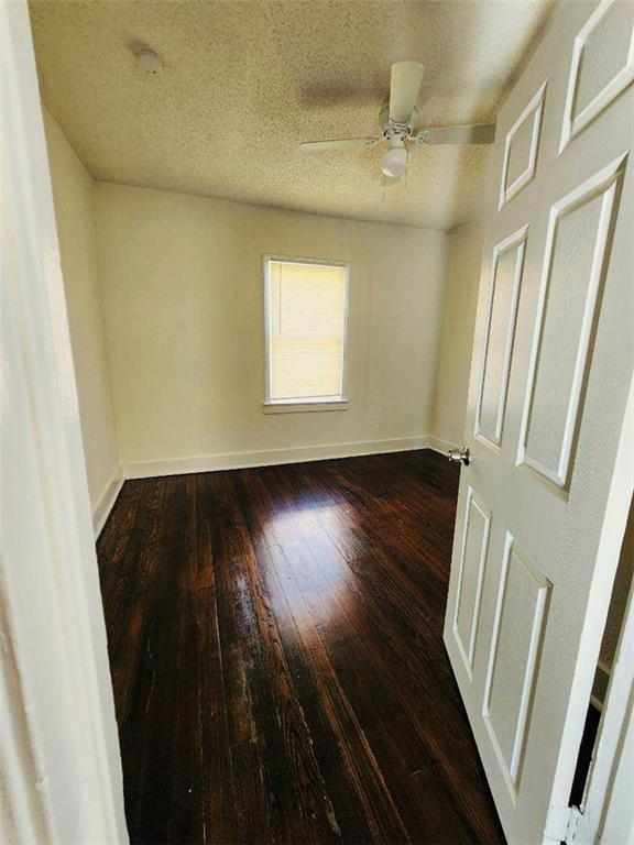 unfurnished room with ceiling fan, dark hardwood / wood-style flooring, and a textured ceiling