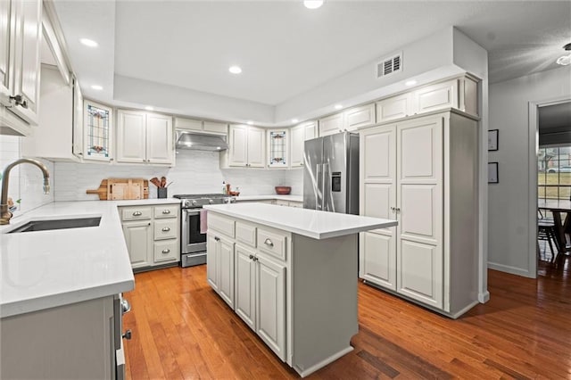 kitchen featuring sink, light hardwood / wood-style flooring, stainless steel appliances, a center island, and decorative backsplash