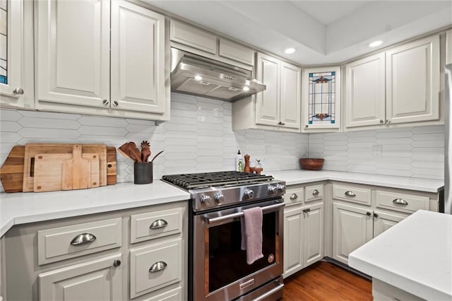 kitchen with decorative backsplash, white cabinets, and high end stove