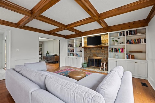 living room featuring coffered ceiling, hardwood / wood-style floors, beam ceiling, and a fireplace