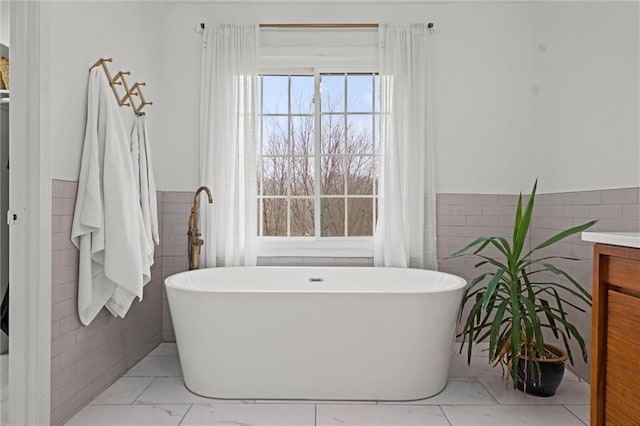 bathroom featuring a tub to relax in, tile walls, and vanity