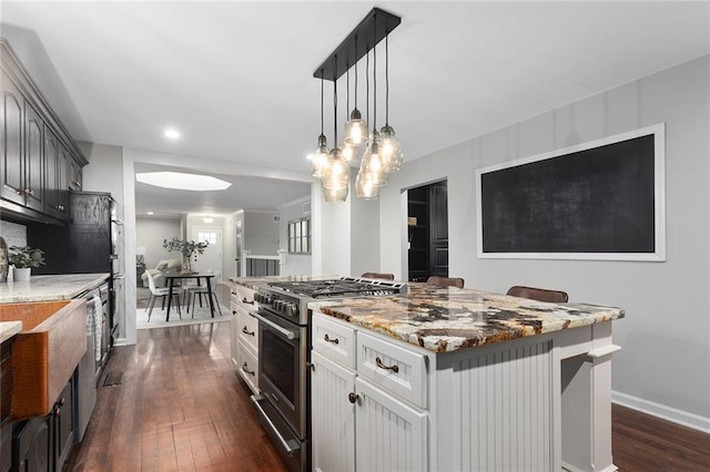 kitchen with hanging light fixtures, a kitchen island, white cabinets, and high end range