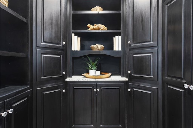 bar featuring light stone counters and built in shelves