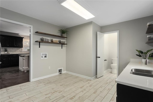 laundry area with hookup for a washing machine, sink, and light hardwood / wood-style flooring