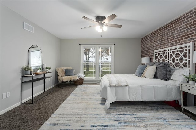 bedroom featuring ceiling fan, brick wall, and dark colored carpet