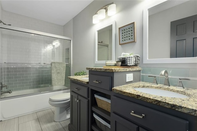 full bathroom featuring vanity, shower / bath combination with glass door, and toilet