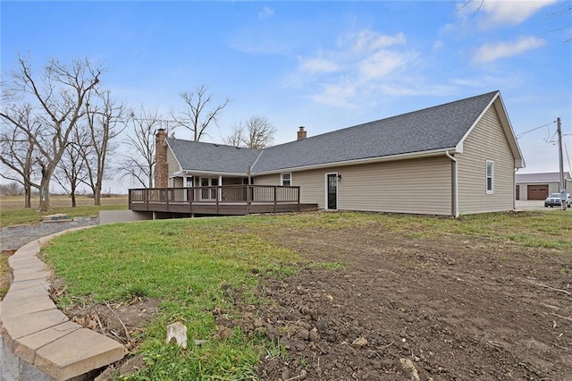 rear view of house with a wooden deck and a lawn