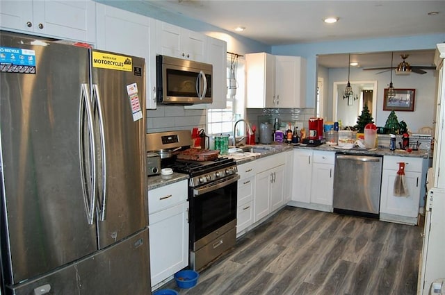 kitchen with dark wood-type flooring, sink, white cabinetry, dark stone countertops, and stainless steel appliances