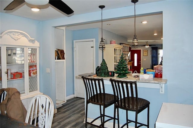 kitchen featuring pendant lighting, ceiling fan, dark hardwood / wood-style flooring, and a breakfast bar area