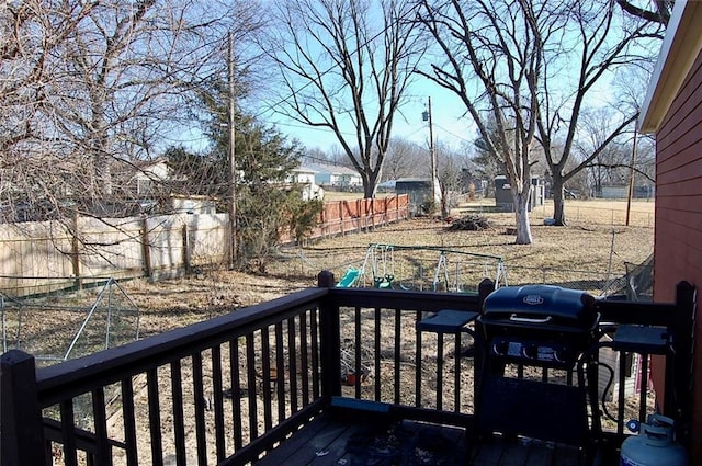 wooden terrace with a playground and area for grilling