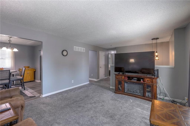 living area with carpet, a textured ceiling, visible vents, and baseboards