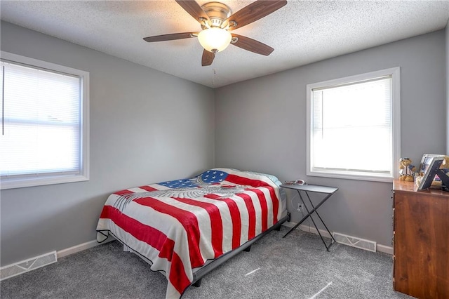 carpeted bedroom with baseboards, visible vents, ceiling fan, and a textured ceiling