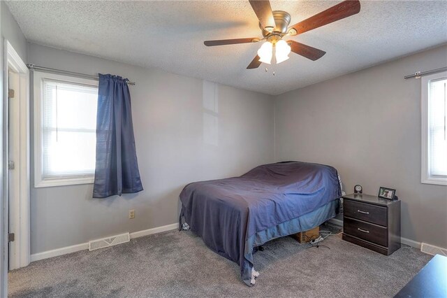 carpeted bedroom with a textured ceiling, visible vents, and baseboards