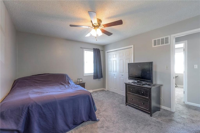 carpeted bedroom featuring baseboards, visible vents, a ceiling fan, a textured ceiling, and a closet