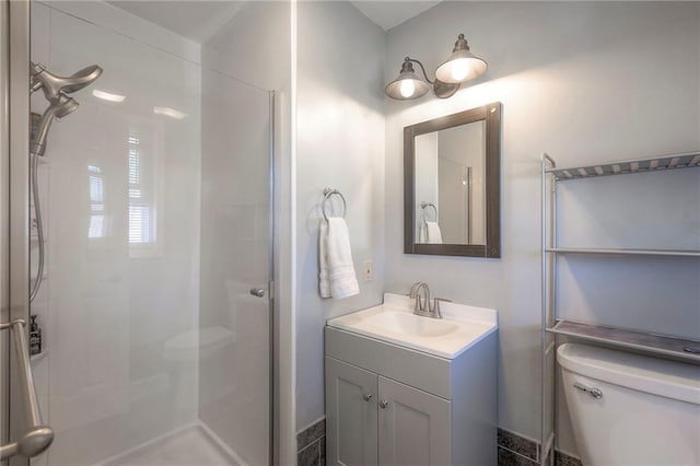 bathroom featuring toilet, a shower stall, and vanity