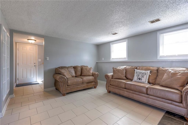 living room featuring visible vents, a textured ceiling, baseboards, and light tile patterned flooring