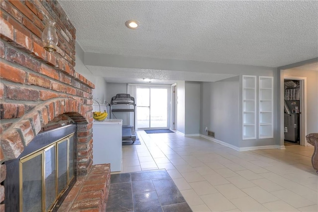 interior space featuring visible vents, a brick fireplace, a textured ceiling, baseboards, and tile patterned floors