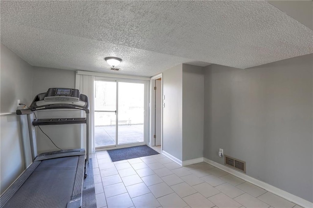 workout room with a textured ceiling, visible vents, and baseboards