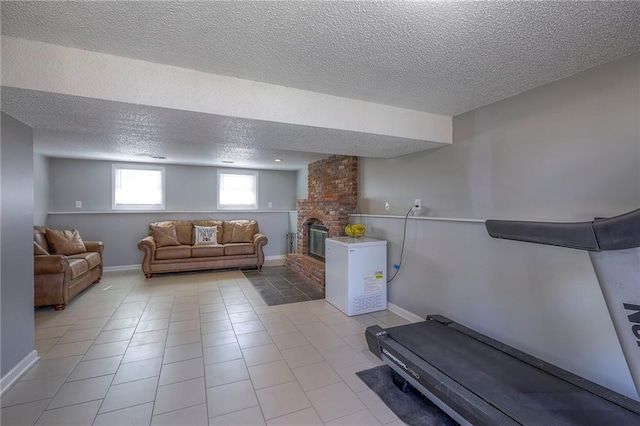 workout area with light tile patterned floors, a textured ceiling, a brick fireplace, and baseboards